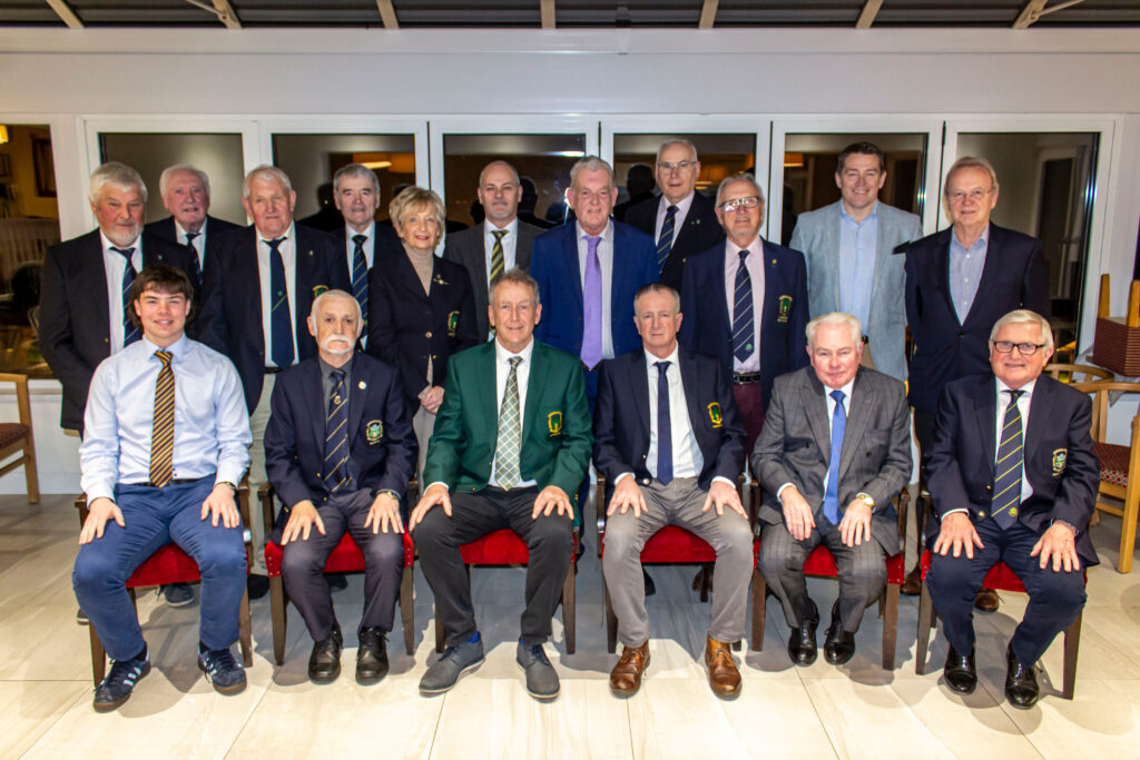 Seventeen club committee members in blazers and ties pose indoors for a formal group photo.