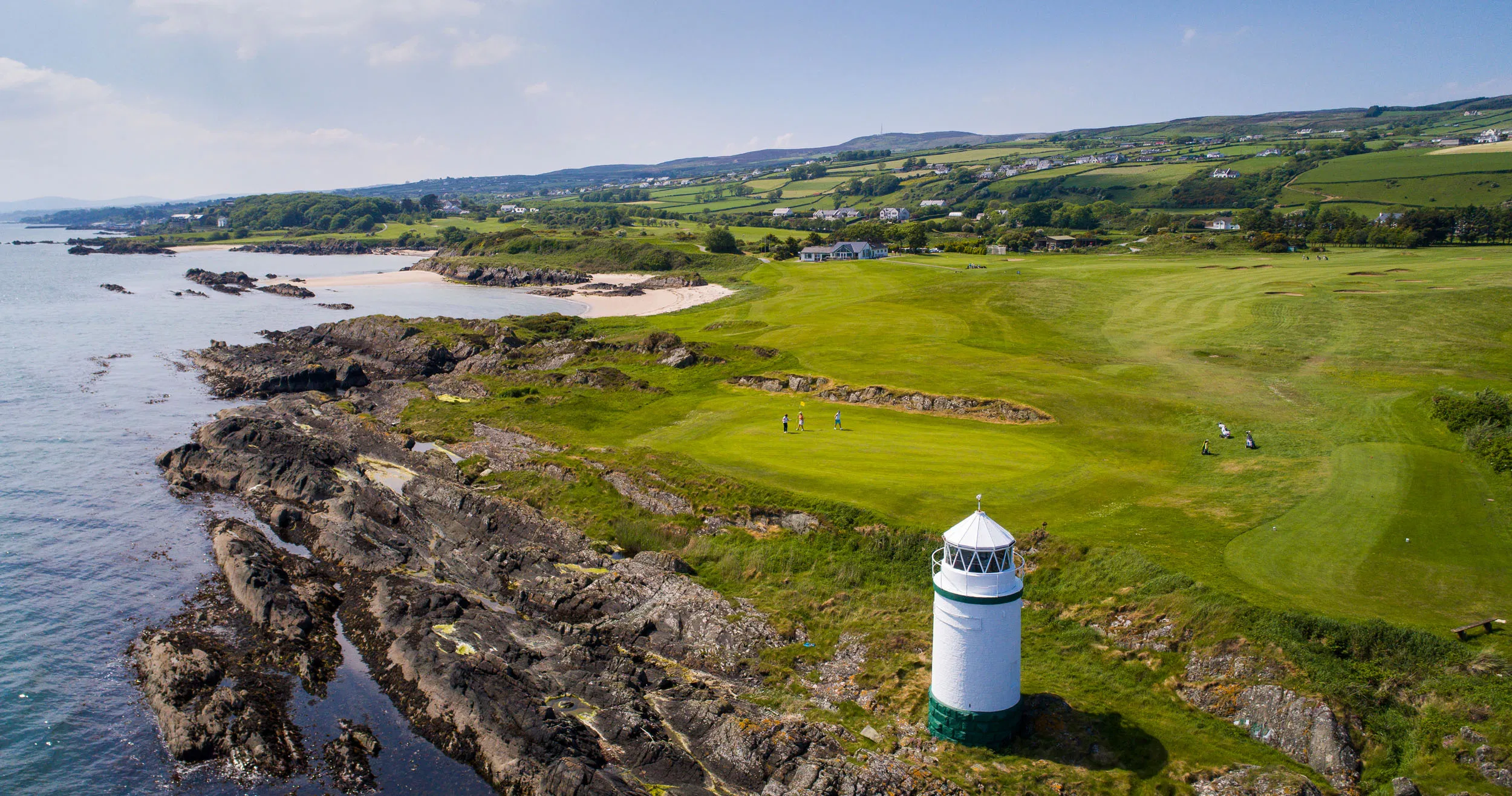 Lighthouse by a links golf course on Donegal’s rocky coast, golfers on the fairway with Atlantic views.