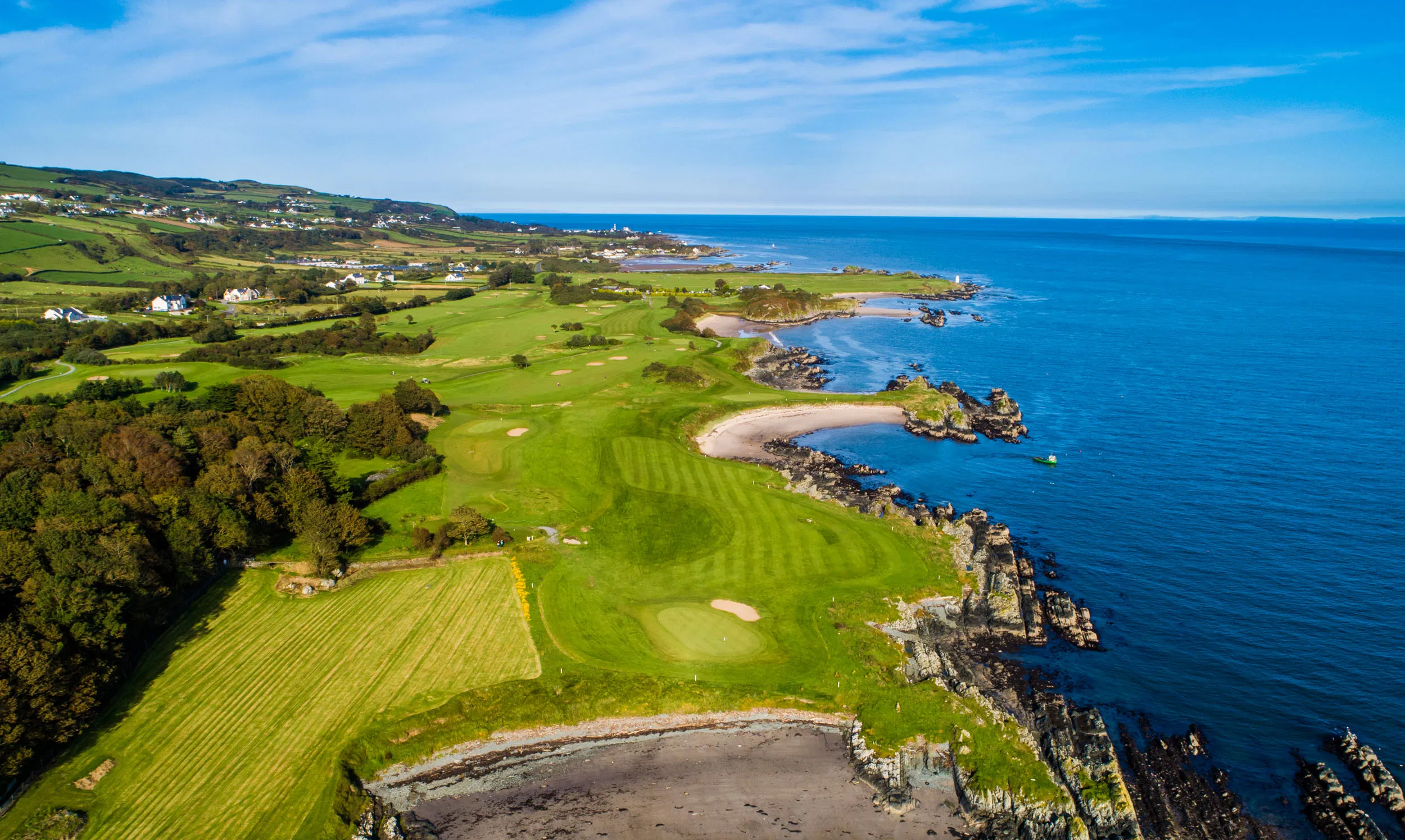Clifftop links golf course on the Irish coast, with rolling fairways, sandy coves and bright blue Atlantic