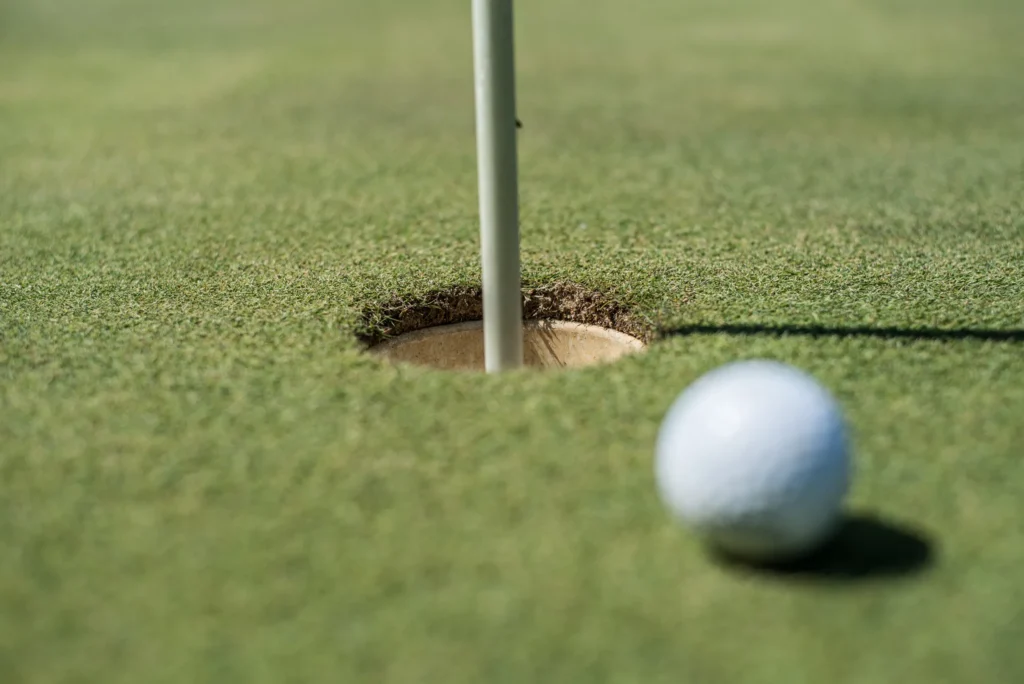 Golf ball just shy of the hole on the putting green, pin in place