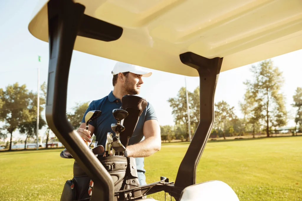 Golfer in a buggy checking his clubs on a sunny golf course