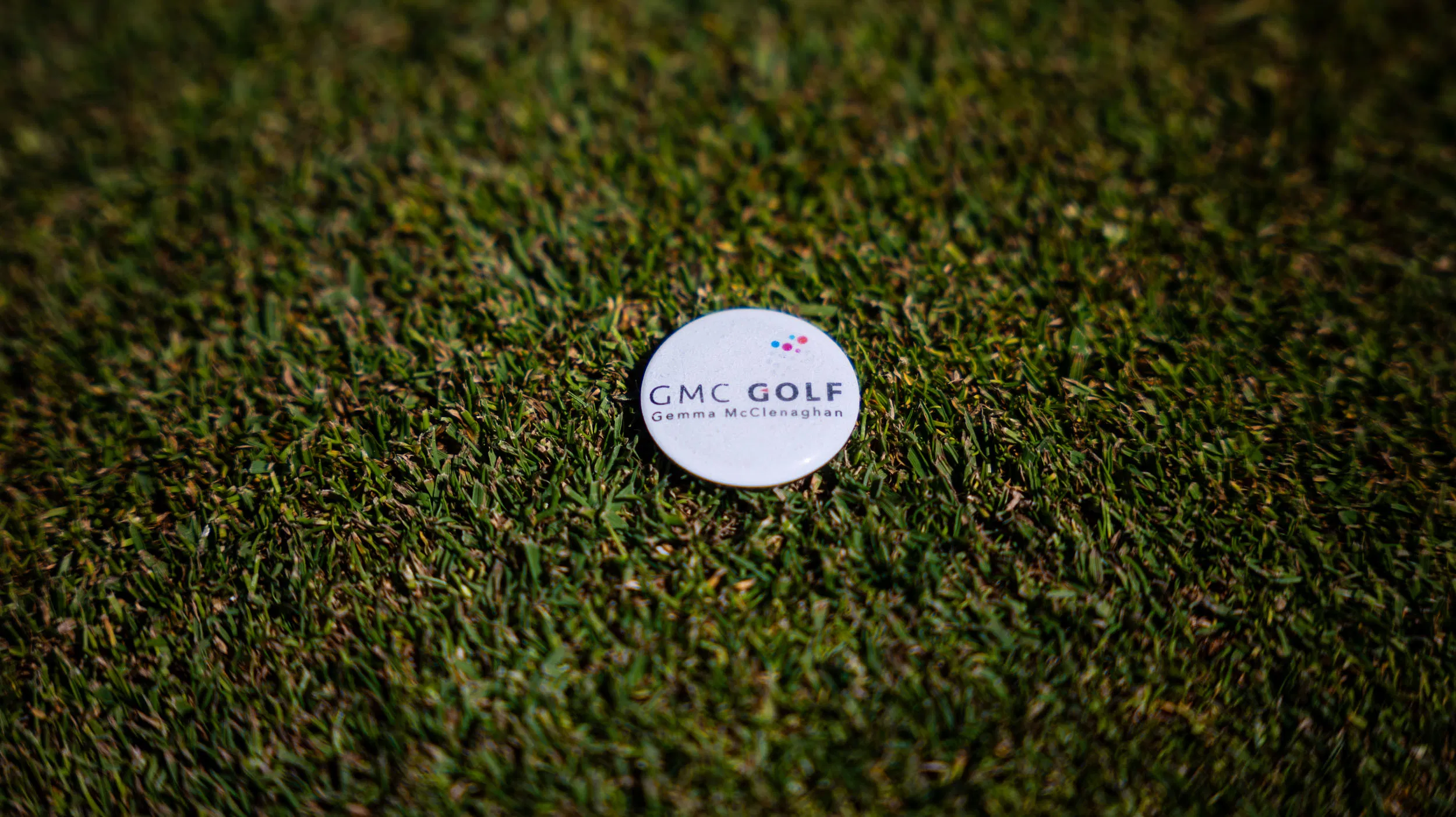 White GMC Golf badge on lush green grass.